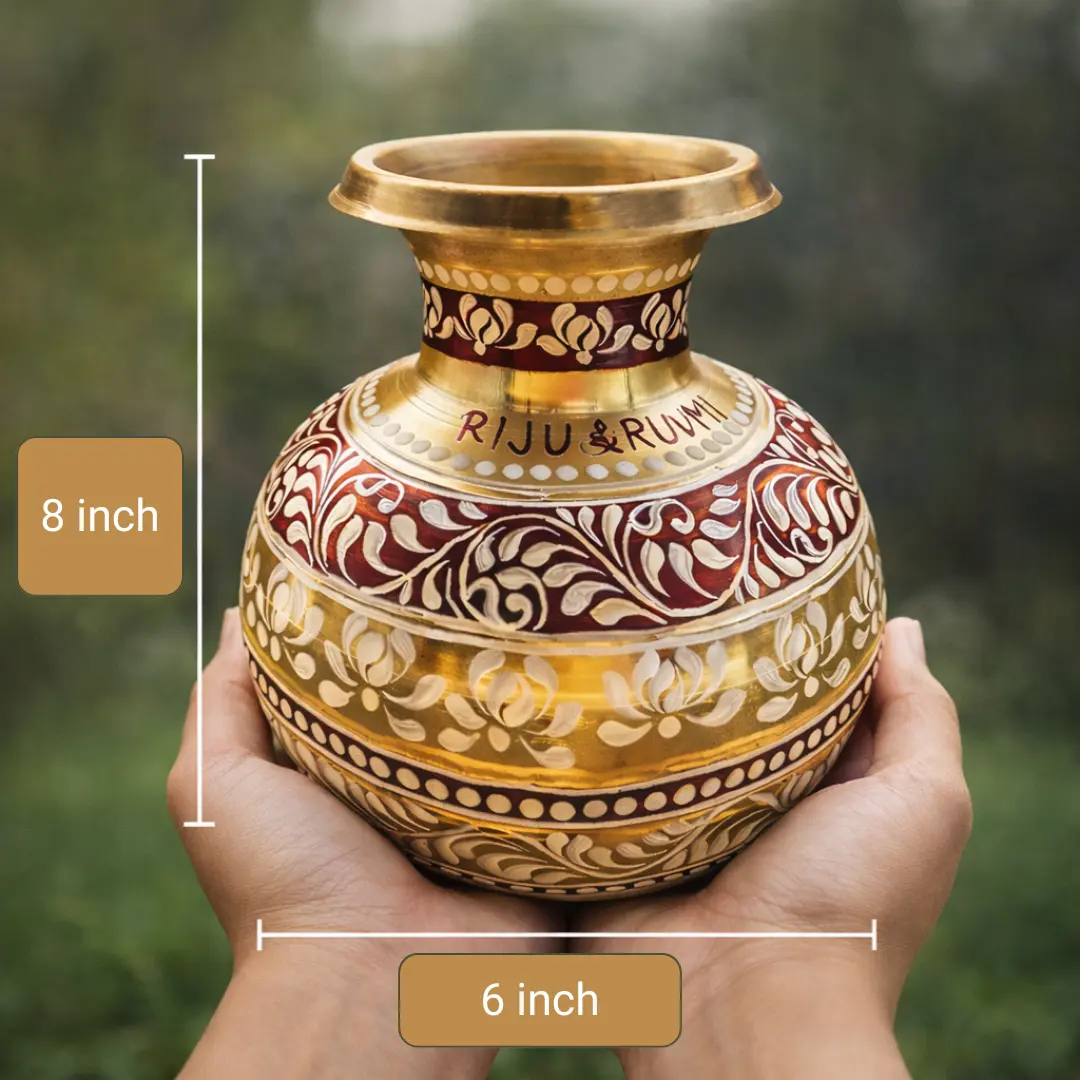 Hand-painted brass Kalshi with traditional maroon and white Kolka floral designs, 8 inches tall, displayed on a neutral beige background with marigold flowers.